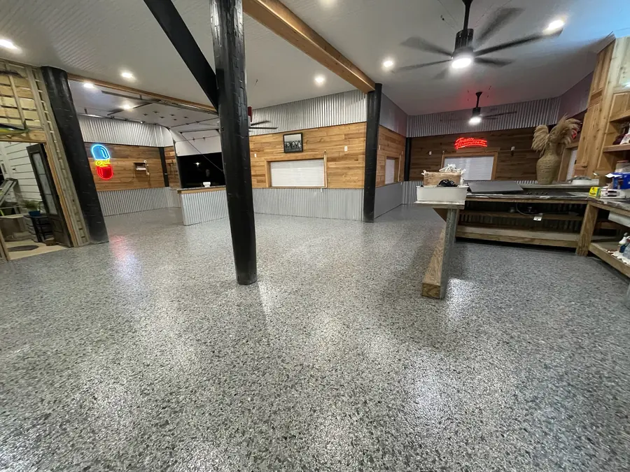 Wide grey flake floor under exposed beams in a pine-walled camp