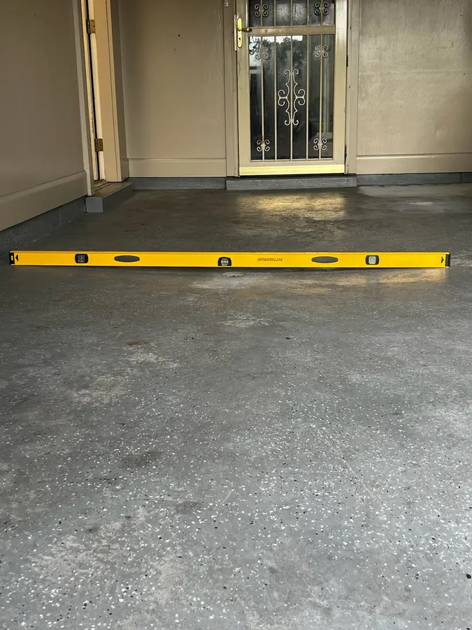 Checking a garage slab with a level before coating