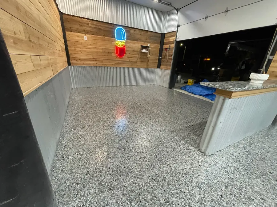 Flake floor meeting a tin-clad bar in a camp hangout room
