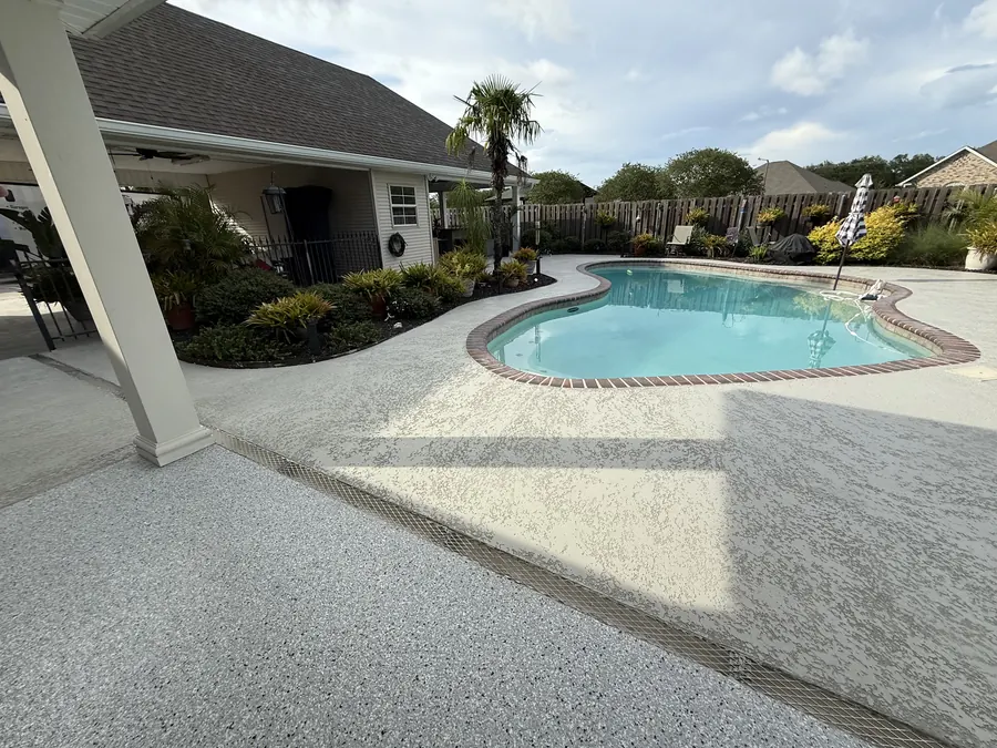 Light flake pool deck coating around a backyard pool, seen from the covered patio