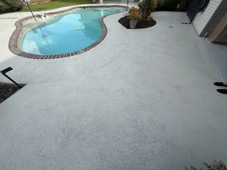 Pool deck finished in a light flake coating around a kidney-shaped pool