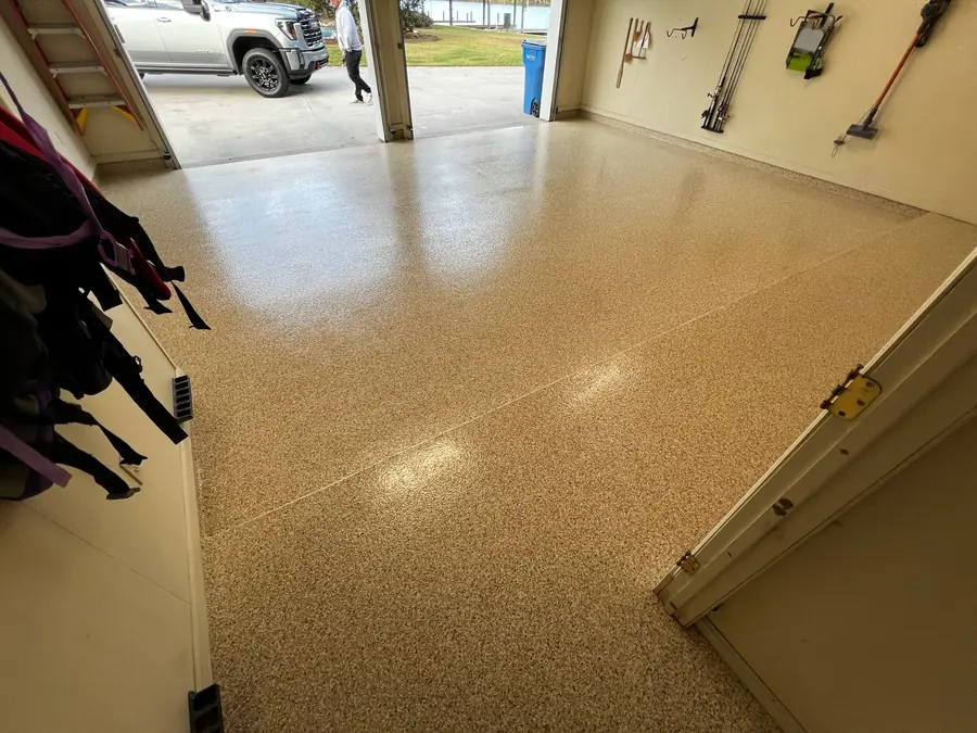 Two-car garage with a tan flake floor, door open to the drive