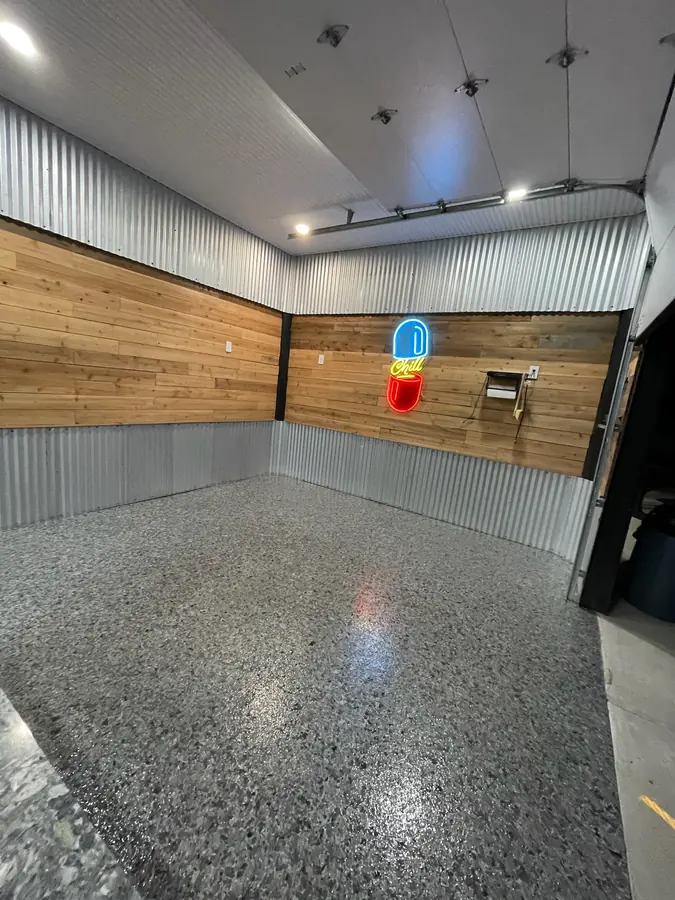 Flake floor under a neon sign in a corrugated tin corner